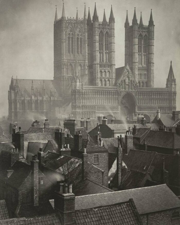 “Vista histórica de una catedral gótica imponente sobre techos urbanos durante época pasada.”
