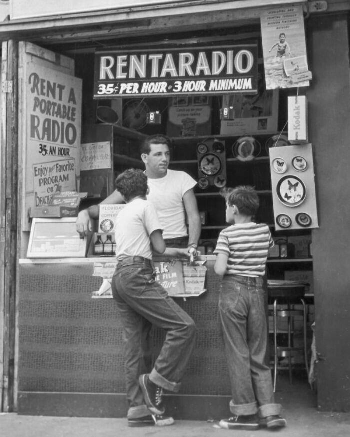 Dos niños conversan en un puesto de renta de radios antiguas, destacando cambios en hábitos modernos.