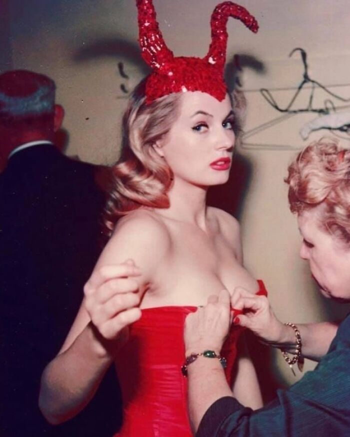 "Mujer con vestido rojo y cuernos brillantes en una foto antigua que muestra moda en cambio."