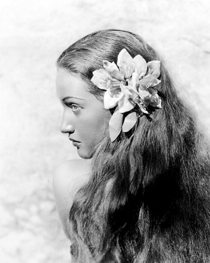 Mujer vintage con flor en el cabello, un cambio notable en la moda antigua.