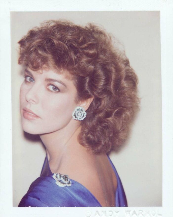 Una mujer con vestido azul y aretes grandes, en una foto antigua mostrando cómo ha cambiado el estilo hoy en día.