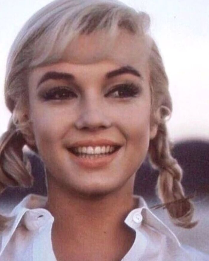 Sonriente mujer rubia con trenzas y camisa blanca en una foto antigua mostrando algo que ha cambiado.