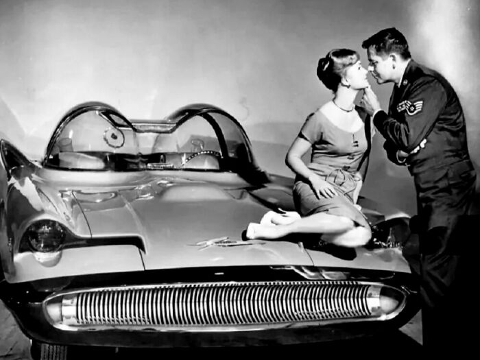 Mujer y hombre besándose sobre un coche retro, ilustración de cómo ha cambiado la moda y los vehículos.