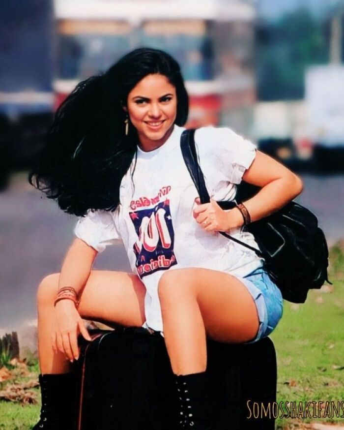 Mujer joven sentada al aire libre, luciendo camiseta y mochila, mostrando moda antigua que ha cambiado.