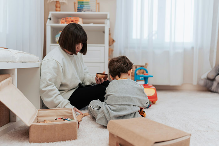 Mujer y niño jugando en una habitación luminosa, evocando momentos de infancia.