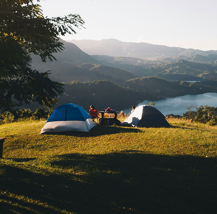 Personas acampando junto a un lago al atardecer, reflejando vivencias pasadas.