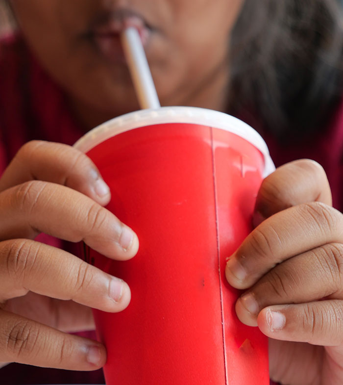 Niño bebiendo de un vaso rojo con sorbete, ilustrando un choque cultural.