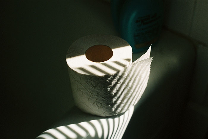 Rollo de papel higiénico iluminado por sombras en un baño, ilustrando choques culturales inesperados.