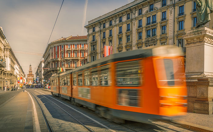 Tranvía naranja en movimiento por una ciudad europea, ilustrando un choque cultural urbano.