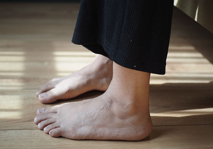 Pies descalzos sobre suelo de madera, relacionados con choques culturales y costumbres del hogar.