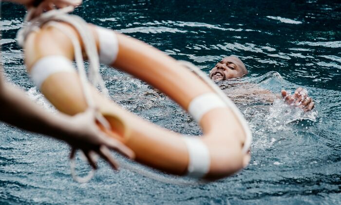 Hombre en el agua recibiendo un salvavidas.