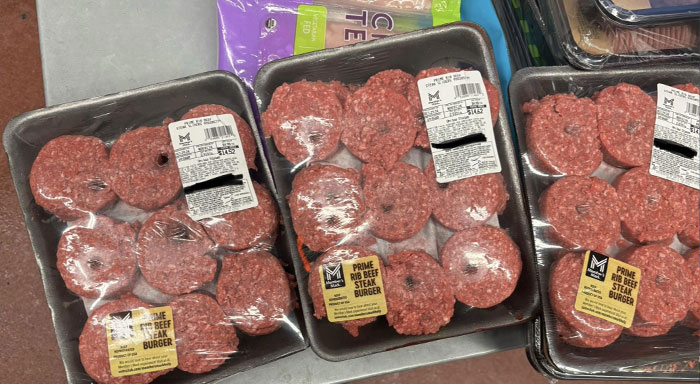 Paquetes de hamburguesas de carne de res prime rib en bandejas cubiertas con film plástico listas para la venta.