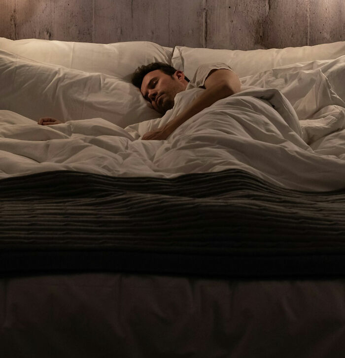 Hombre durmiendo en una cama grande, ilustrando una noche de paranoia y terror real.