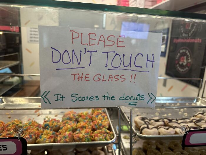 Aviso legal divertido en vitrina de donas que pide no tocar el vidrio para no asustar a las donas en la tienda.