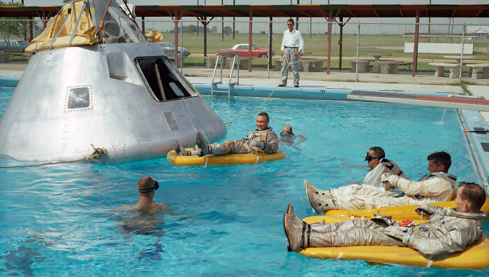 Astronautas en entrenamiento acuático junto a un módulo espacial, escena aparentemente normal con historia inquietante.