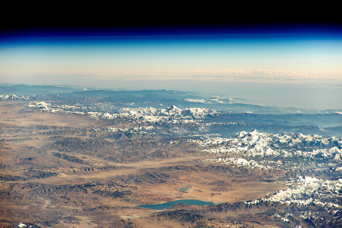Vista aérea de montañas nevadas y un lago desde una perspectiva distinta.
