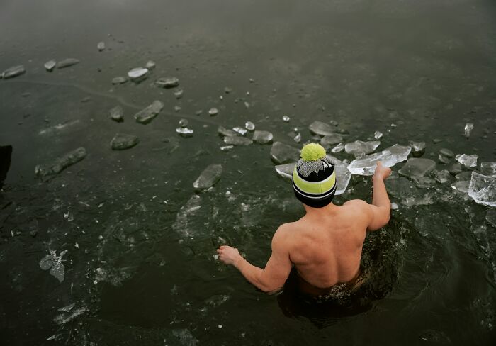 Hombre en agua helada, usando gorro. Escenario de supervivencia que destaca la importancia de conocer datos útiles para salvar vidas.