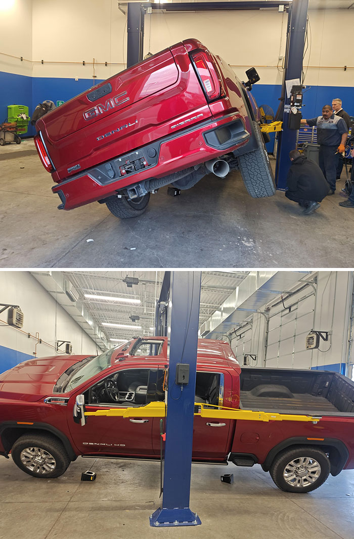 Camioneta GMC roja inclinada en un taller, problemas en el trabajo.