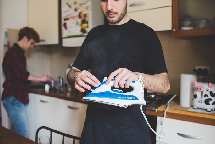 Un hombre en la cocina sosteniendo la plancha de manera descuidada, ejemplificando a parejas consideradas 