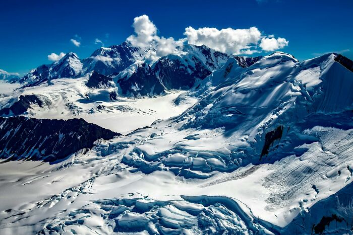Paisaje montañoso nevado bajo un cielo azul brillante.