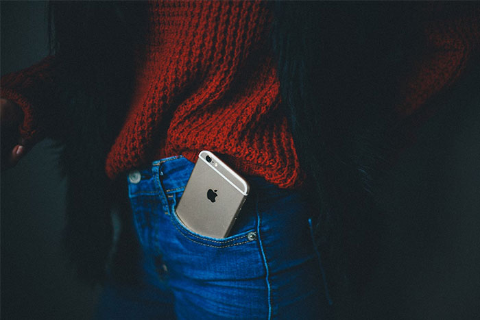 Mujer con suéter rojo y jeans, teléfono en el bolsillo trasero, enfoque en preguntas de hombres a mujeres.