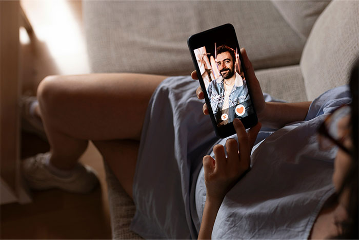 Mujer viendo foto de hombre en app, destacando curiosidades entre hombres y mujeres.