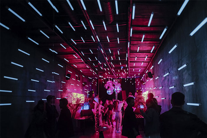Personas en una sala iluminada por luces LED, destacando coincidencias increíbles en el ambiente de la fiesta.