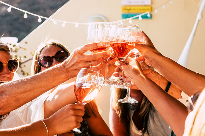 Personas brindando al aire libre con copas de vino rosado, simbolizando coincidencias sorprendentes.