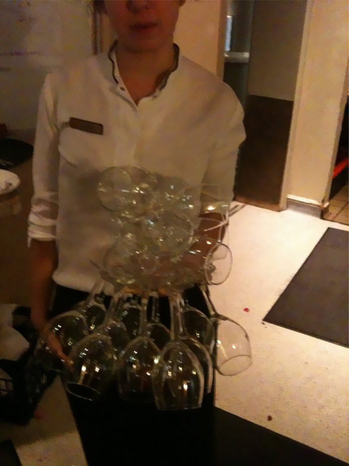 Una persona sosteniendo una torre de copas de vino para una foto sorprendente.
