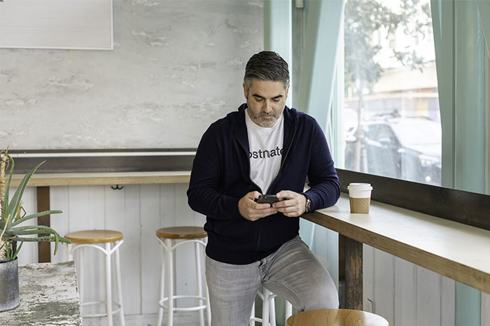 Hombre usando móvil en una cafetería, ejemplo de errores en redes sociales.
