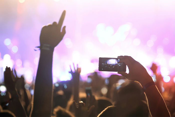 Personas grabando en un concierto con sus teléfonos, ilustrando fallos en redes sociales.