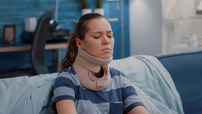 Mujer con collarín sentada en un sofá, representando errores en redes sociales.