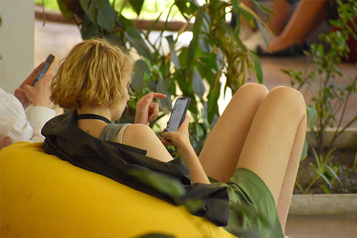 Persona en sofá inflable amarillo revisando redes sociales en móvil, ilustrando fallos comunes al publicar.