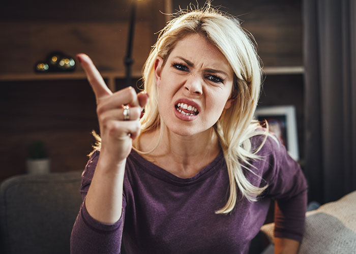 Mujer enfadada señalando, representa conflicto entre amigos.