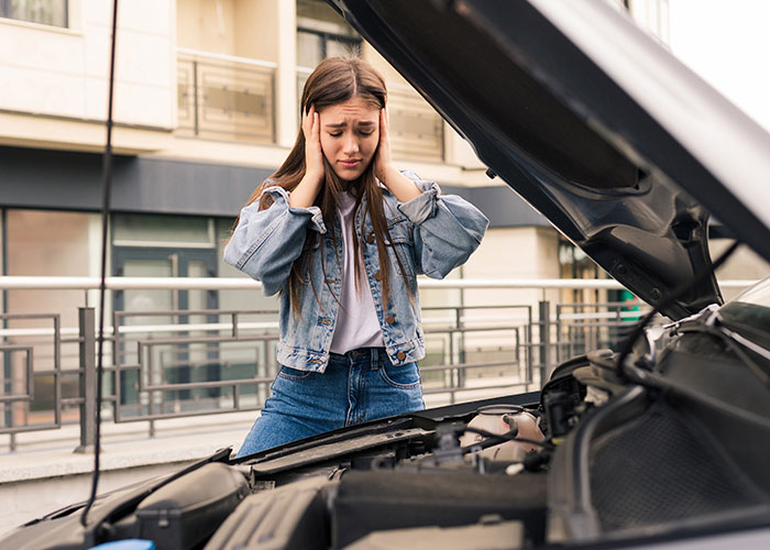 Una mujer preocupada con el auto abierto, símbolo de amistades engañosas.