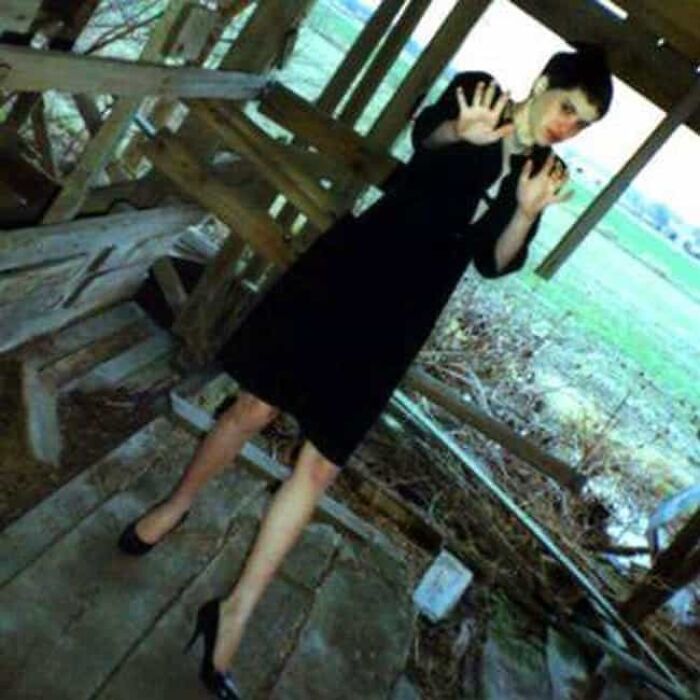 Mujer en un cobertizo, con vestido negro, en una foto que parece normal pero tiene una historia inquietante.