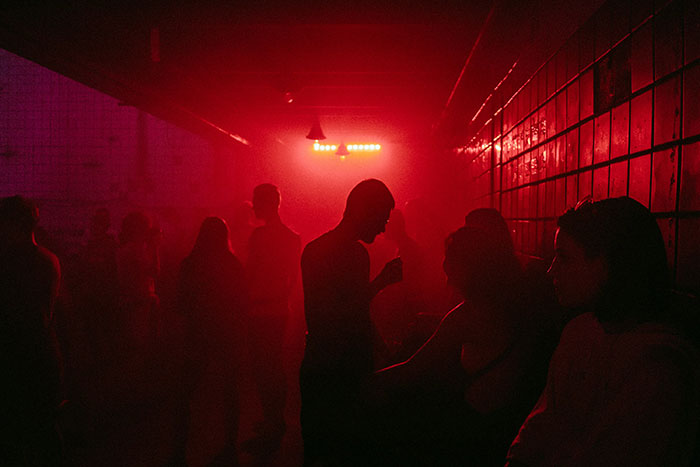 Personas en una fiesta con luces rojas, símbolo de decisiones espontáneas que cambiaron sus vidas y su destino.