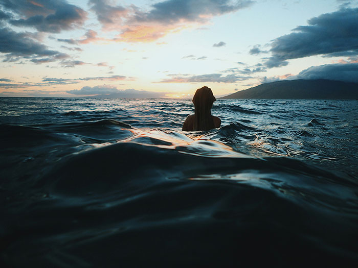 Persona nadando en el mar al atardecer, imagen relacionada con decisiones espontáneas que salvaron vidas.