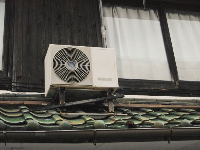 Aire acondicionado montado en una fachada, simbolizando un típico elemento de clase media en el hogar.