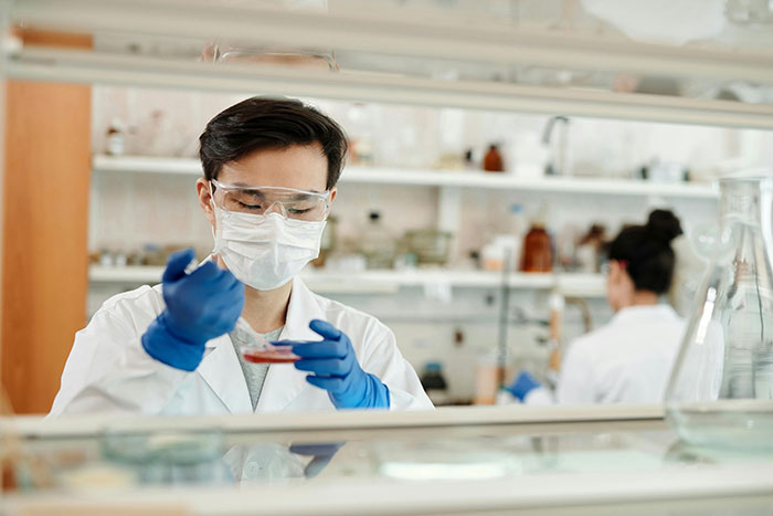Científico en laboratorio trabajando con muestras, ilustrando incógnitas del cuerpo humano.