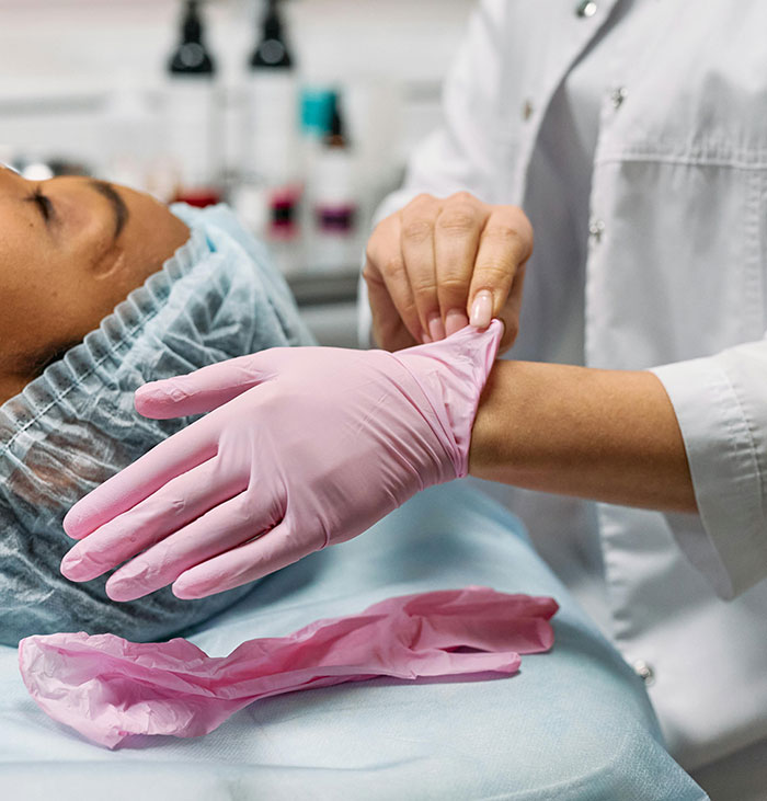 Médico colocándose guantes rosas junto a un paciente en camilla, ilustrando misterios del cuerpo humano.