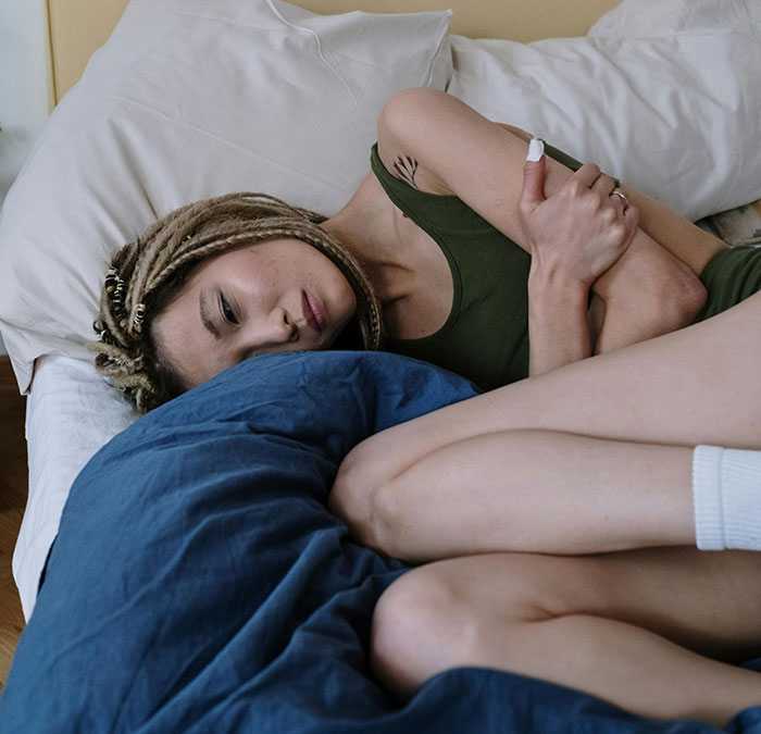 Persona acostada en la cama con gesto pensativo, vinculada al tema del cuerpo humano y sus misterios.