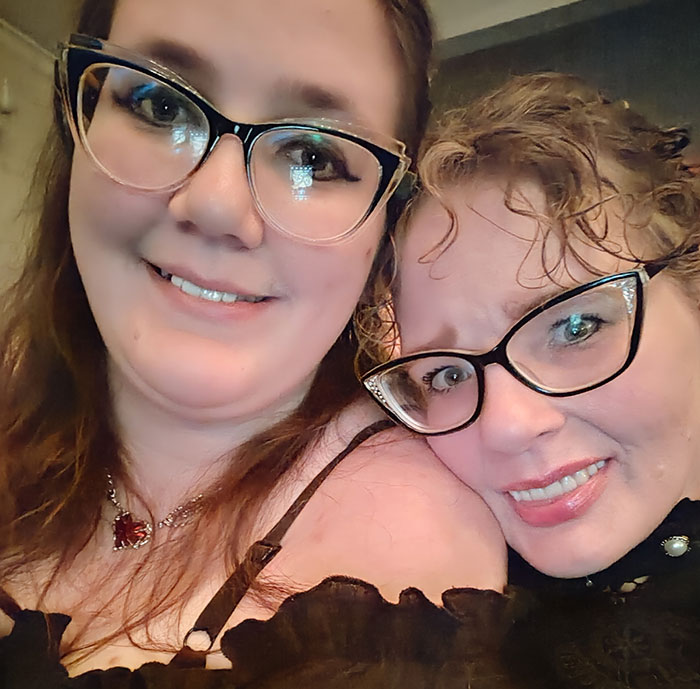 Two women wearing glasses smiling, related to tall cisgender women's workplace issue.
