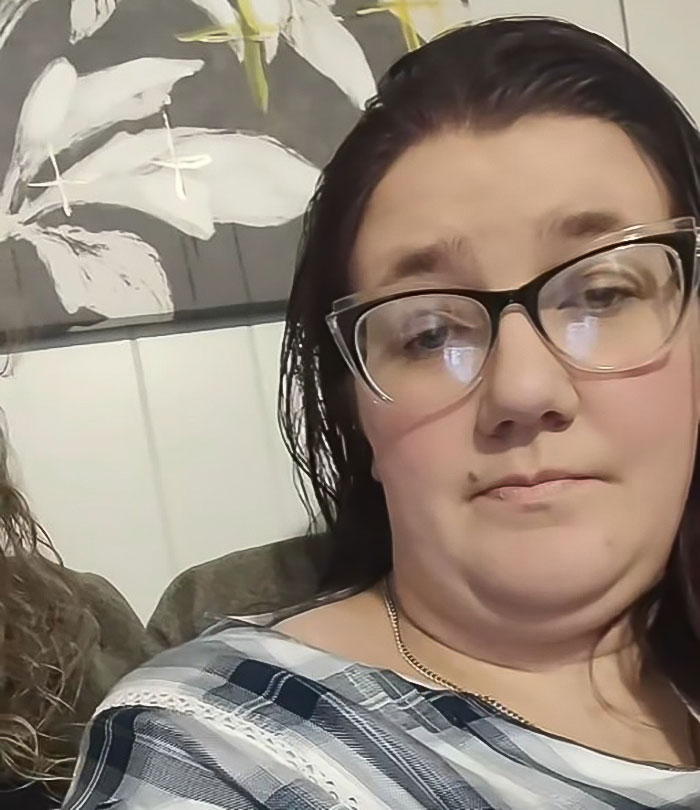 A woman in glasses looks at the camera, reflecting issues faced by tall cisgender women at work.