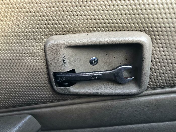 Manilla de puerta de auto reparada con una llave inglesa.