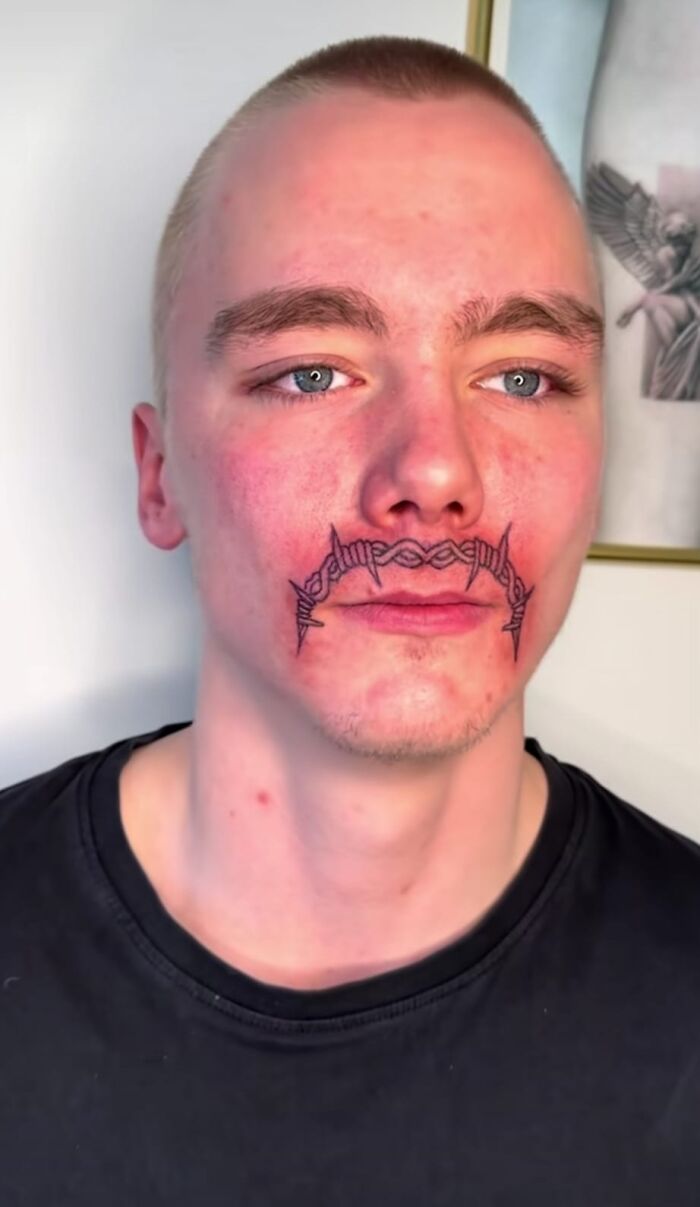 Hombre joven con tatuaje de alambre de púas en el labio superior, expresando su estilo personal.