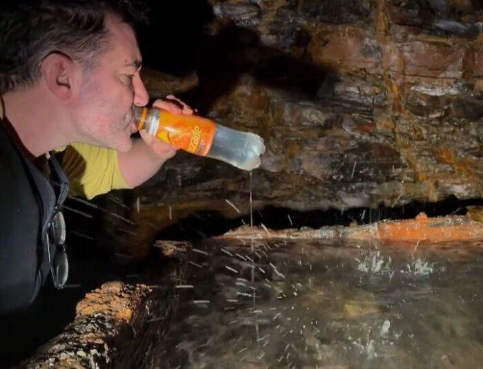 Hombre bebiendo agua de una cueva sin darse cuenta del peligro que lo rodea.