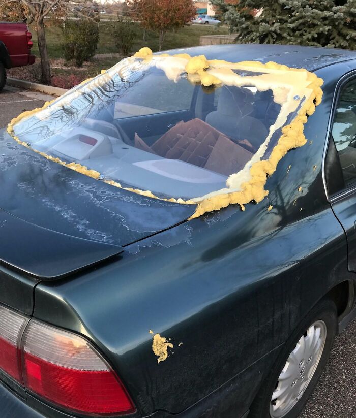 Coche con vidrio trasero mal reparado usando espuma amarilla, un ejemplo de reparaciones empeoradas.