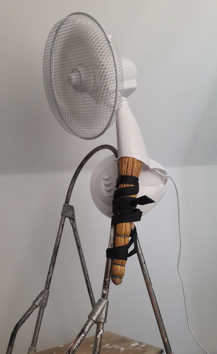 Ventilador reparado con escoba y cinta negra, intento de reparación fallida.