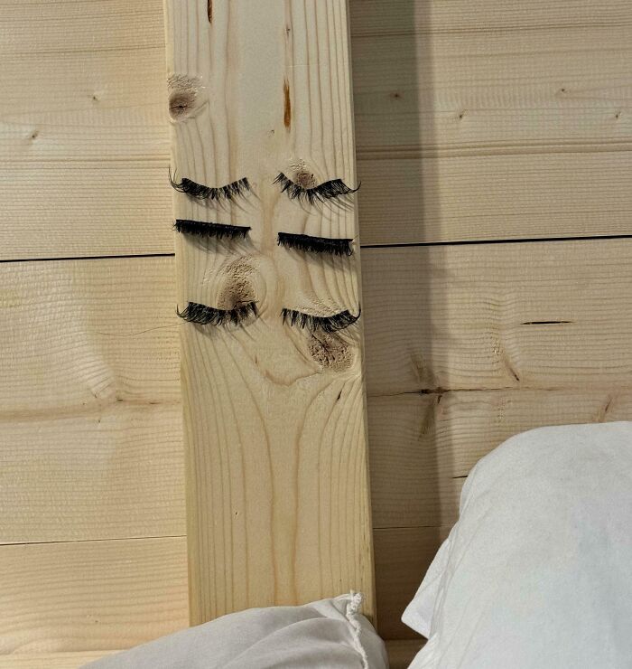 Pestañas en un tablón de madera con nudos parecidos a un rostro, ejemplificando cómo los novios divertidos hacen reír.